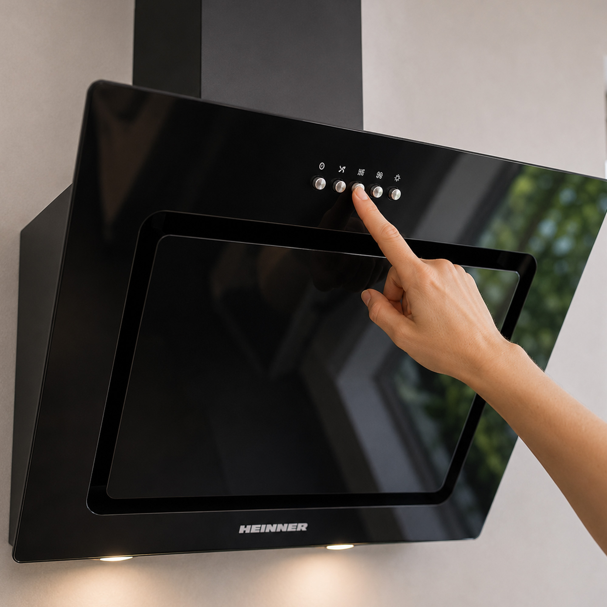 A hand presses the buttons on a modern black Heinner cooker hood.