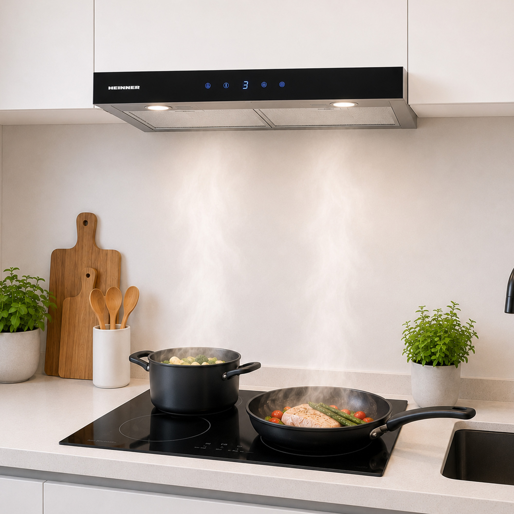 A black cooker hood above a stovetop with steaming pots and a pan, flanked by cutting boards and potted plants.