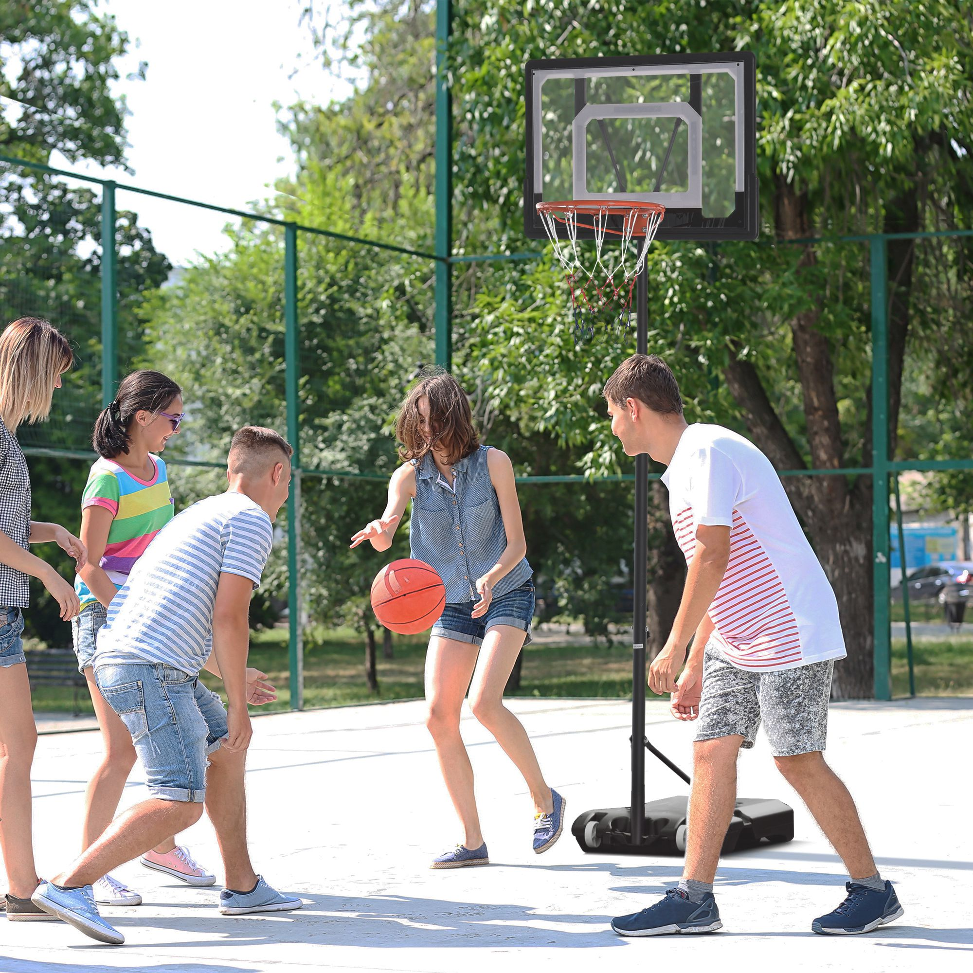 Cinco amigos juegan baloncesto en una cancha al aire libre con una canasta ajustable.