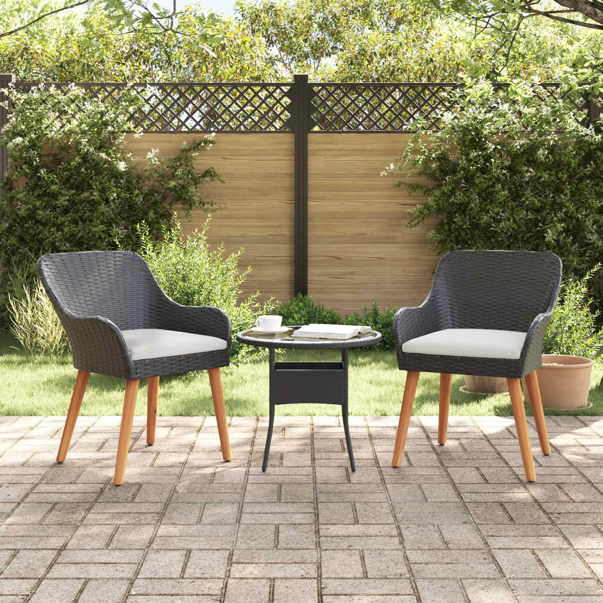 Zwei graue Korbsessel mit Holbeinen und cremefarbenen Kissen stehen auf einer Terrasse mit Tisch.