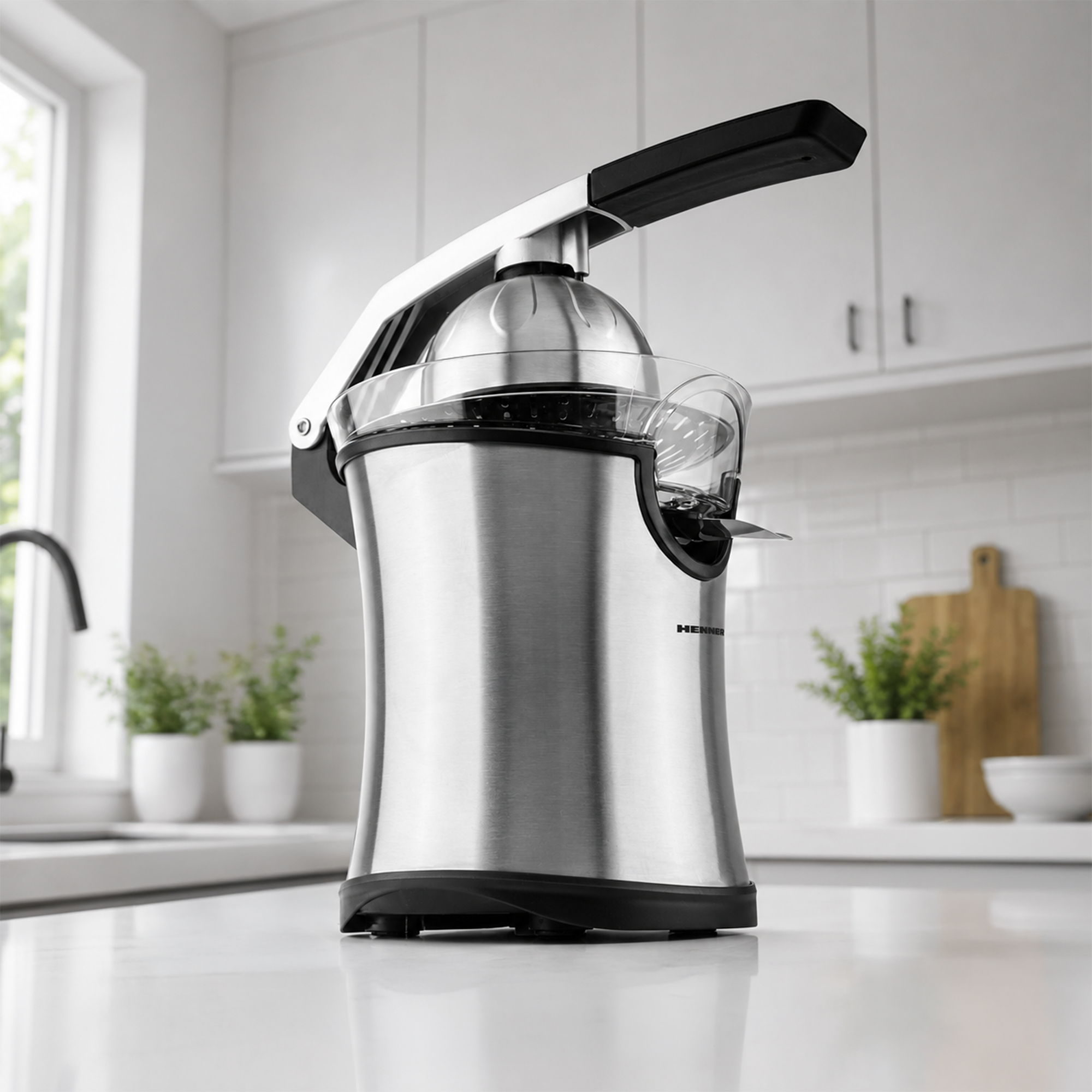 A stainless steel manual citrus juicer sits on a white countertop in a bright kitchen background.