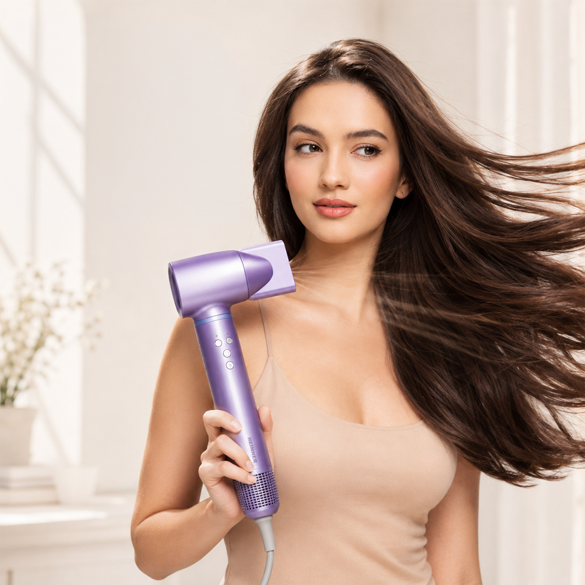 Une femme aux longs cheveux bruns tient un sèche-cheveux violet, ses cheveux volant dans le flux d'air.