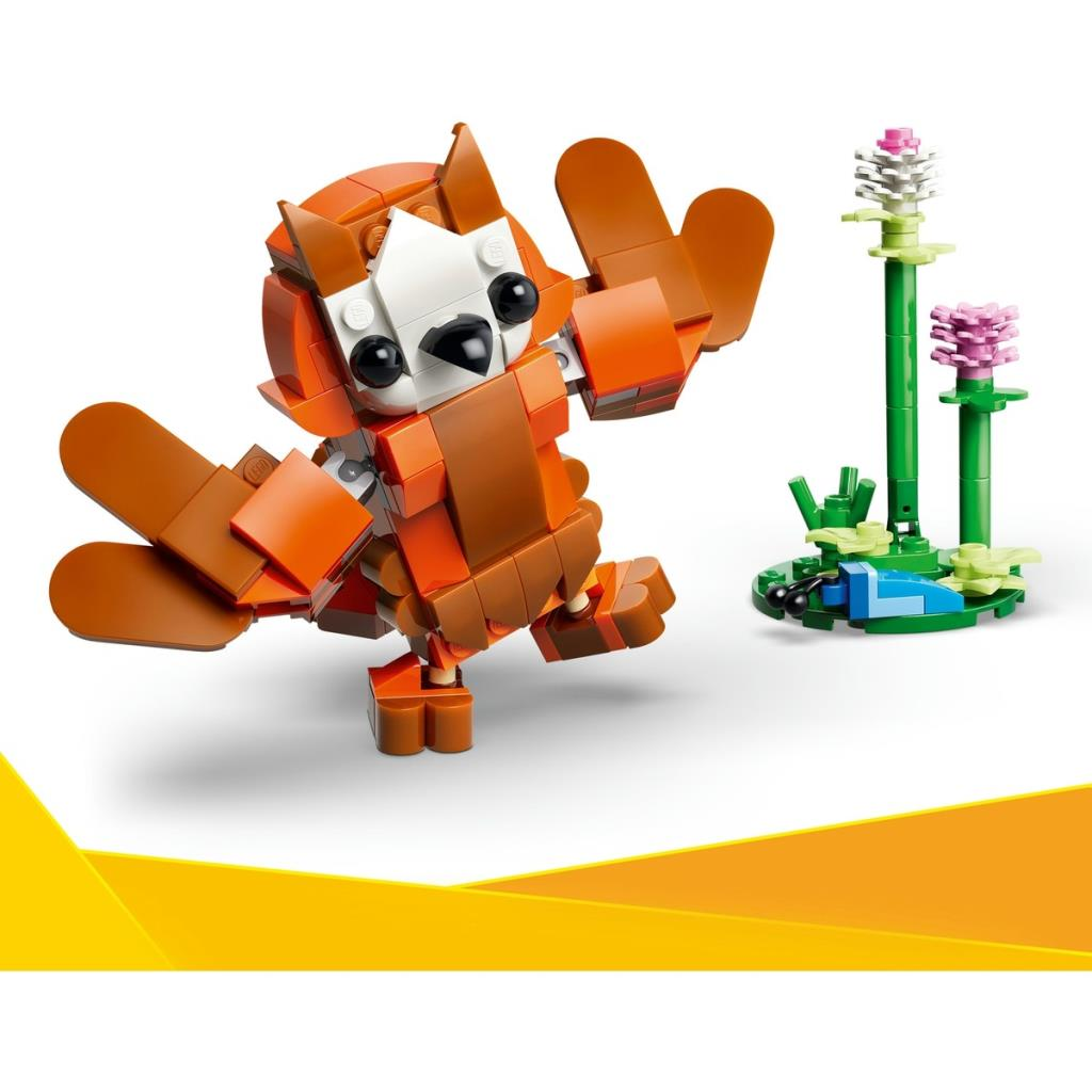 Turuncu ve kahverengi Lego parçalarından yapılmış, beyaz arka planda küçük Lego bitkilerinin yanında duran bir kırmızı panda.