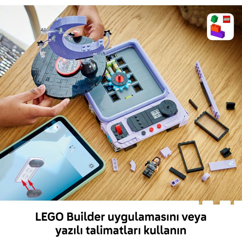 Persona costruisce un set LEGO viola con pezzi e guida app su un tavolo.