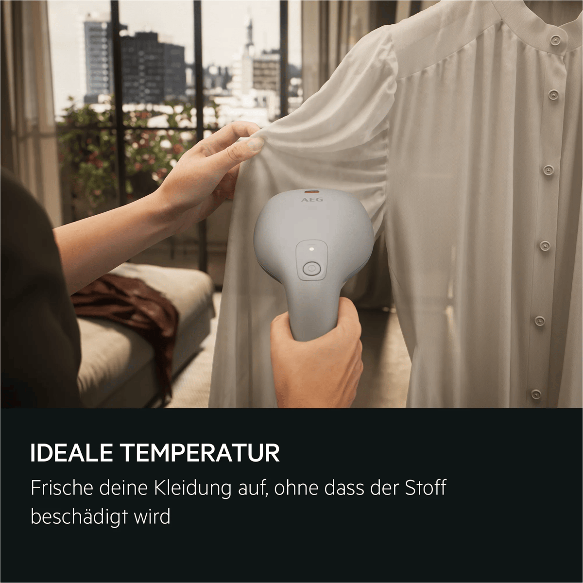 Una persona plancha con vapor una blusa blanca usando un vaporizador de mano gris en una habitación luminosa.