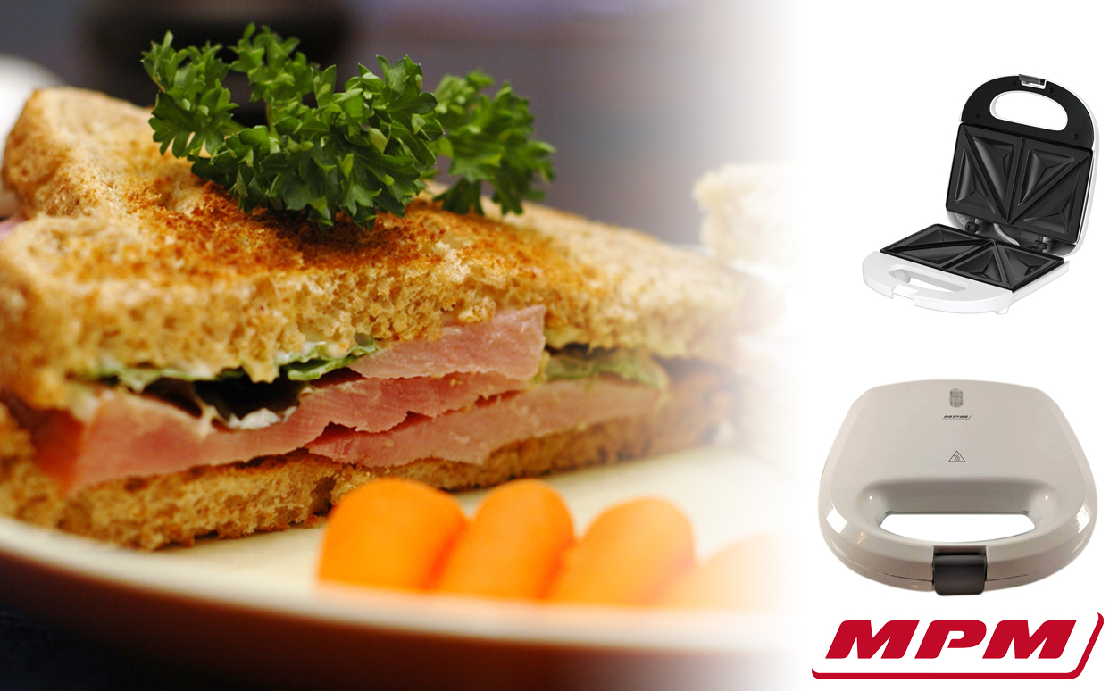 Ein Schinkentoast mit Petersilie und Minikarotten, dazu ein offener und ein geschlossener weißer Sandwichtoaster.