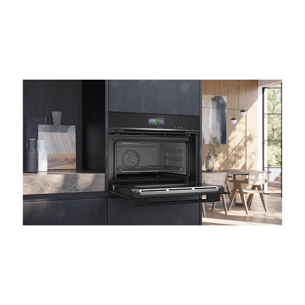Un four encastrable noir avec une porte ouverte dans une cuisine moderne aux murs en bois.