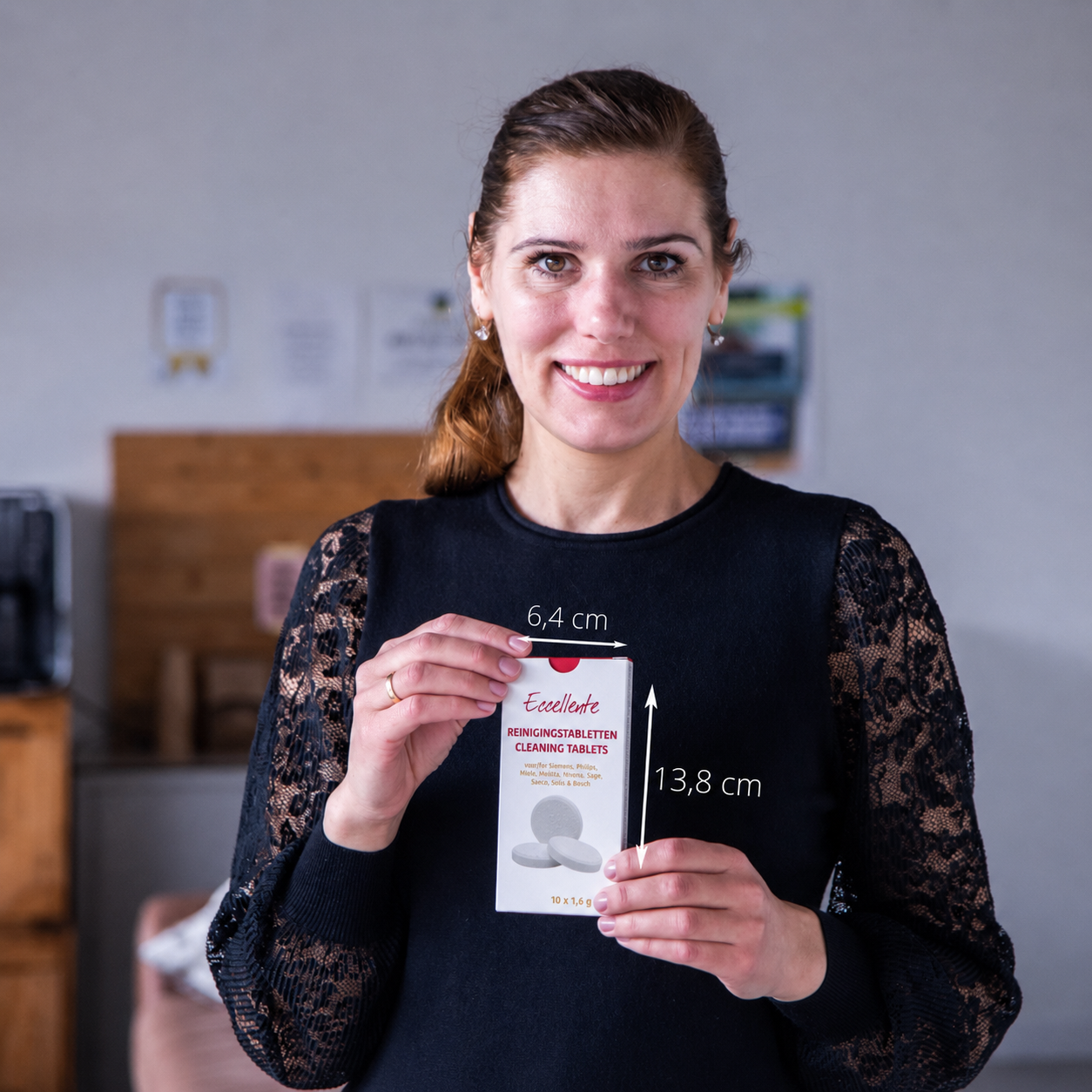 A woman in black holding a product package with dimension markings.