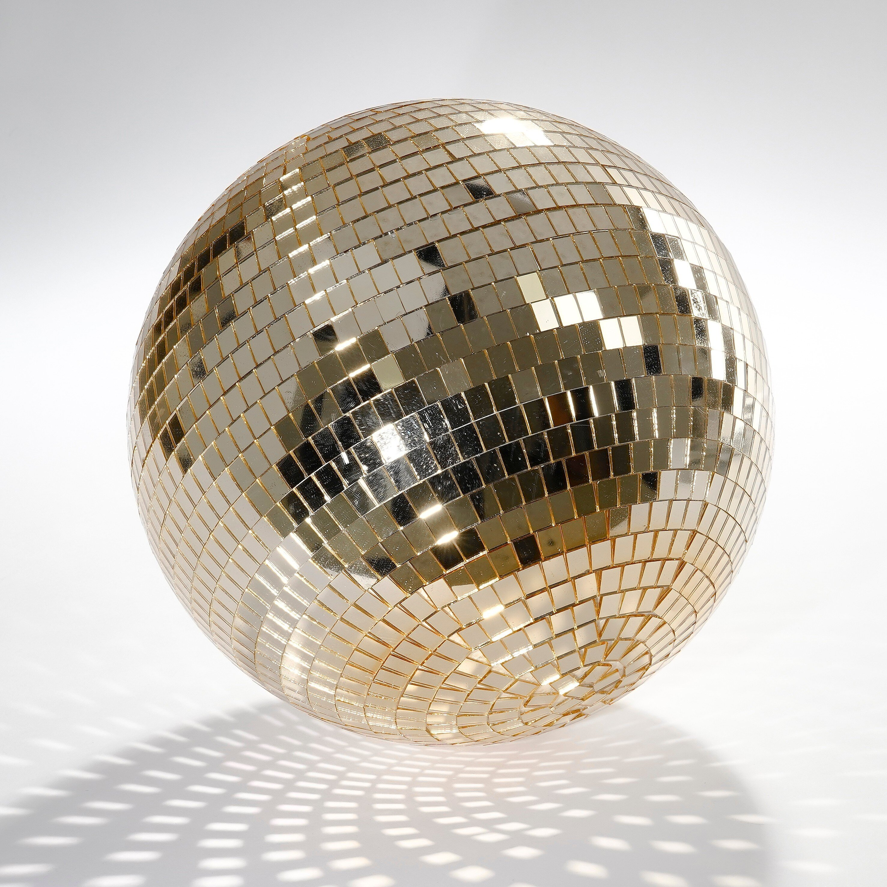 A gold disco ball on a white background with reflecting light.
