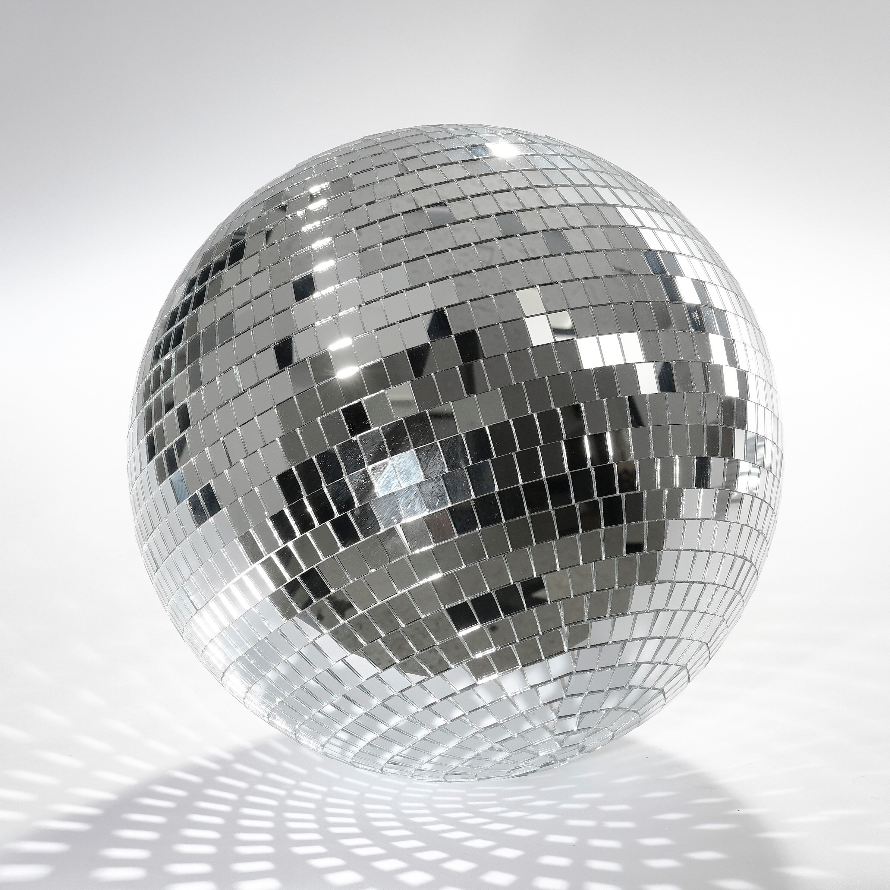 Une boule à facettes brillante sur fond blanc projette des motifs lumineux.