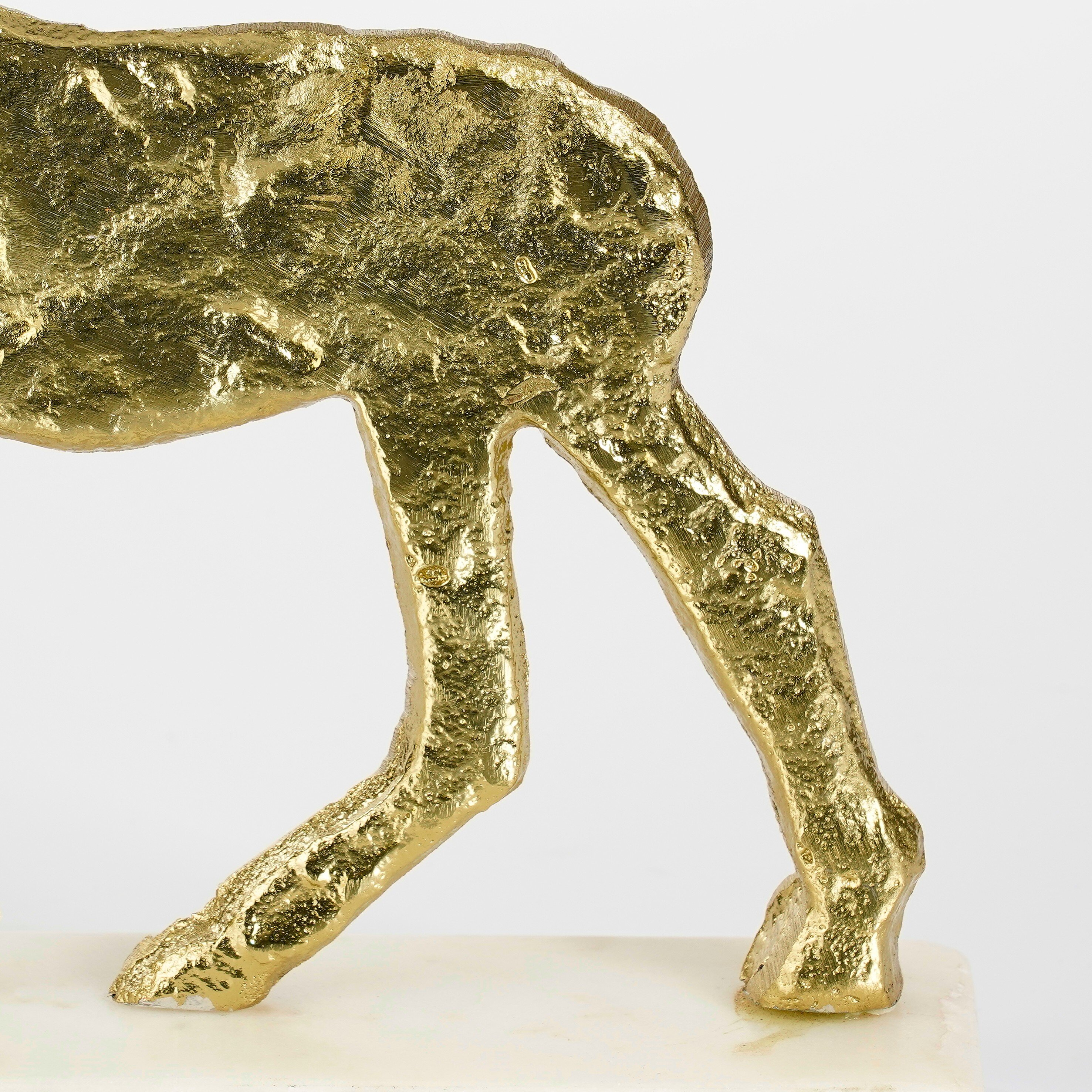 Close-up van gouden dierenpoten op een witte marmeren voet tegen een witte achtergrond.