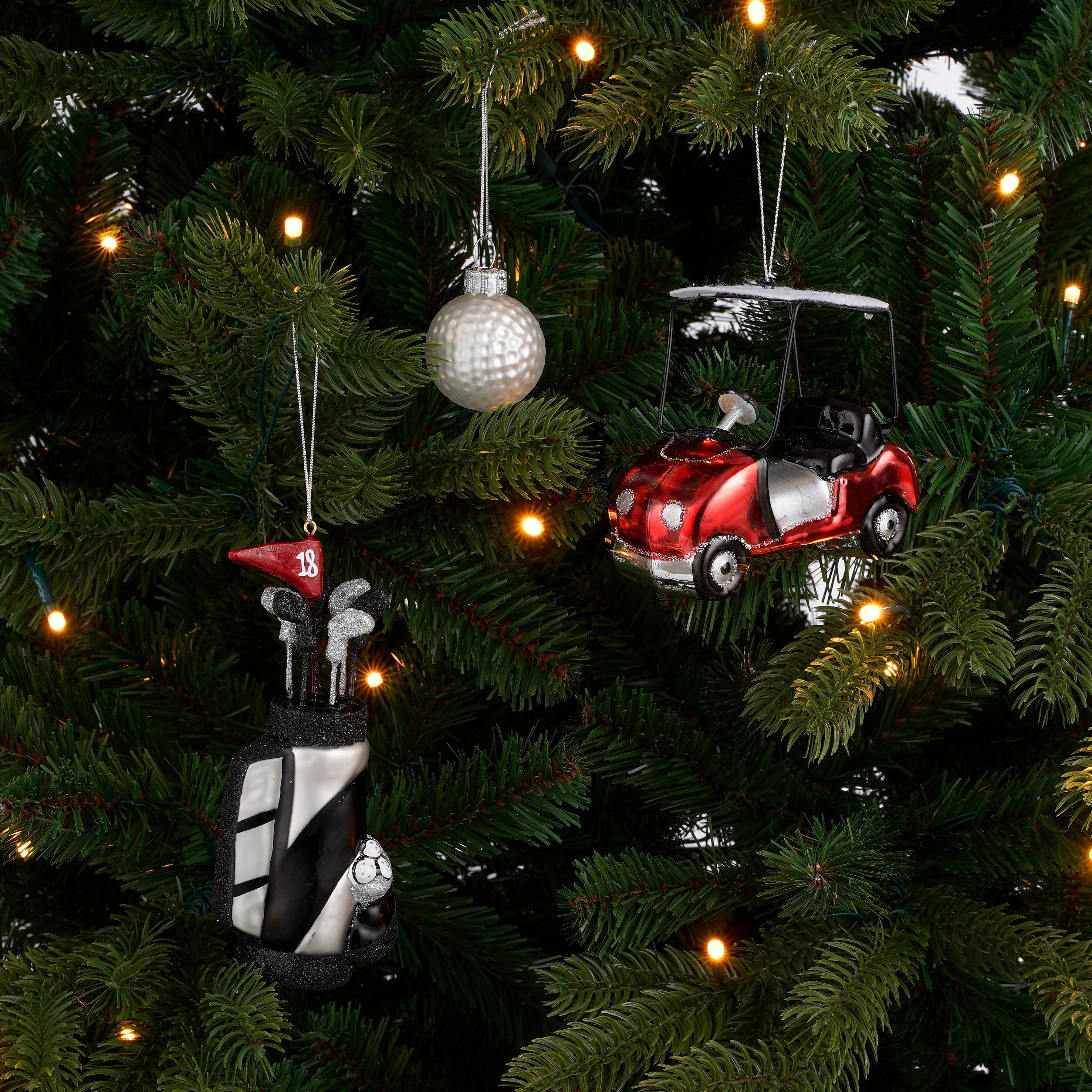 Kerstornamenten in golfstijl, waaronder een golf-tas, bal en golfkar, hangend in een kerstboom.