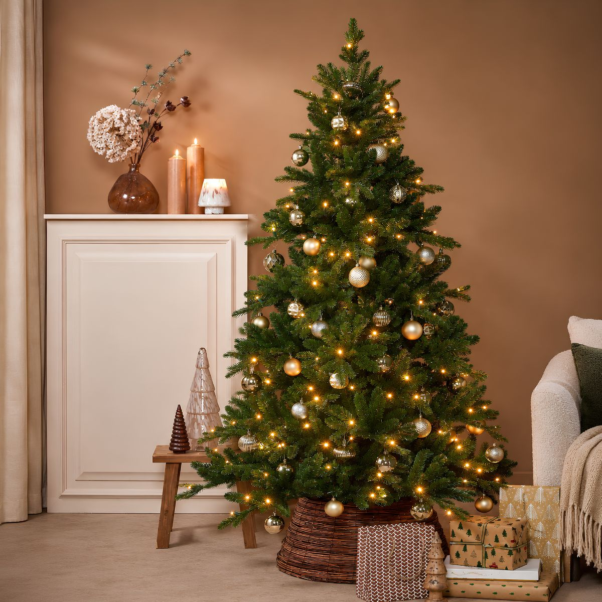 Een versierde kerstboom met lichtjes en kerstballen staat in een kamer, omringd door cadeautjes en kaarsen.