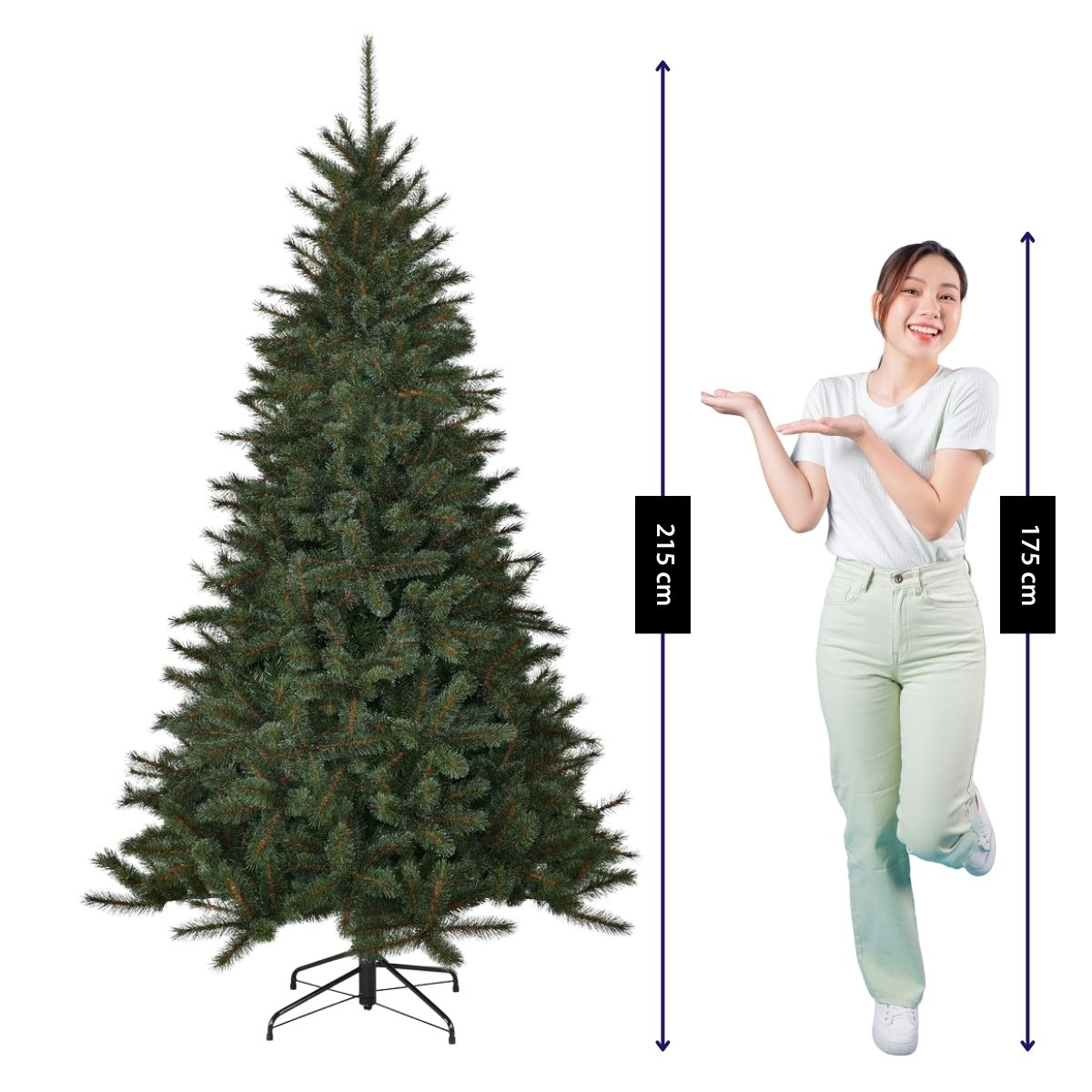 A woman points to a 215 cm tall artificial Christmas tree standing beside her.