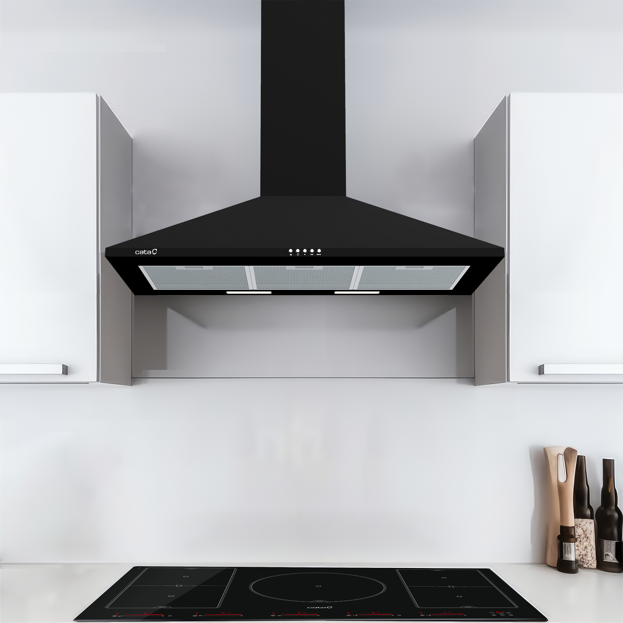 Una cappa aspirante nera è montata tra i mobili da cucina bianchi sopra un piano cottura a induzione nero.