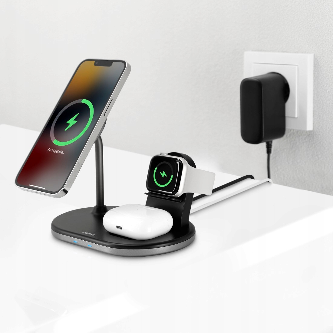 Czarna stacja ładująca ładuje smartfon, smartwatch i słuchawki na białej powierzchni.