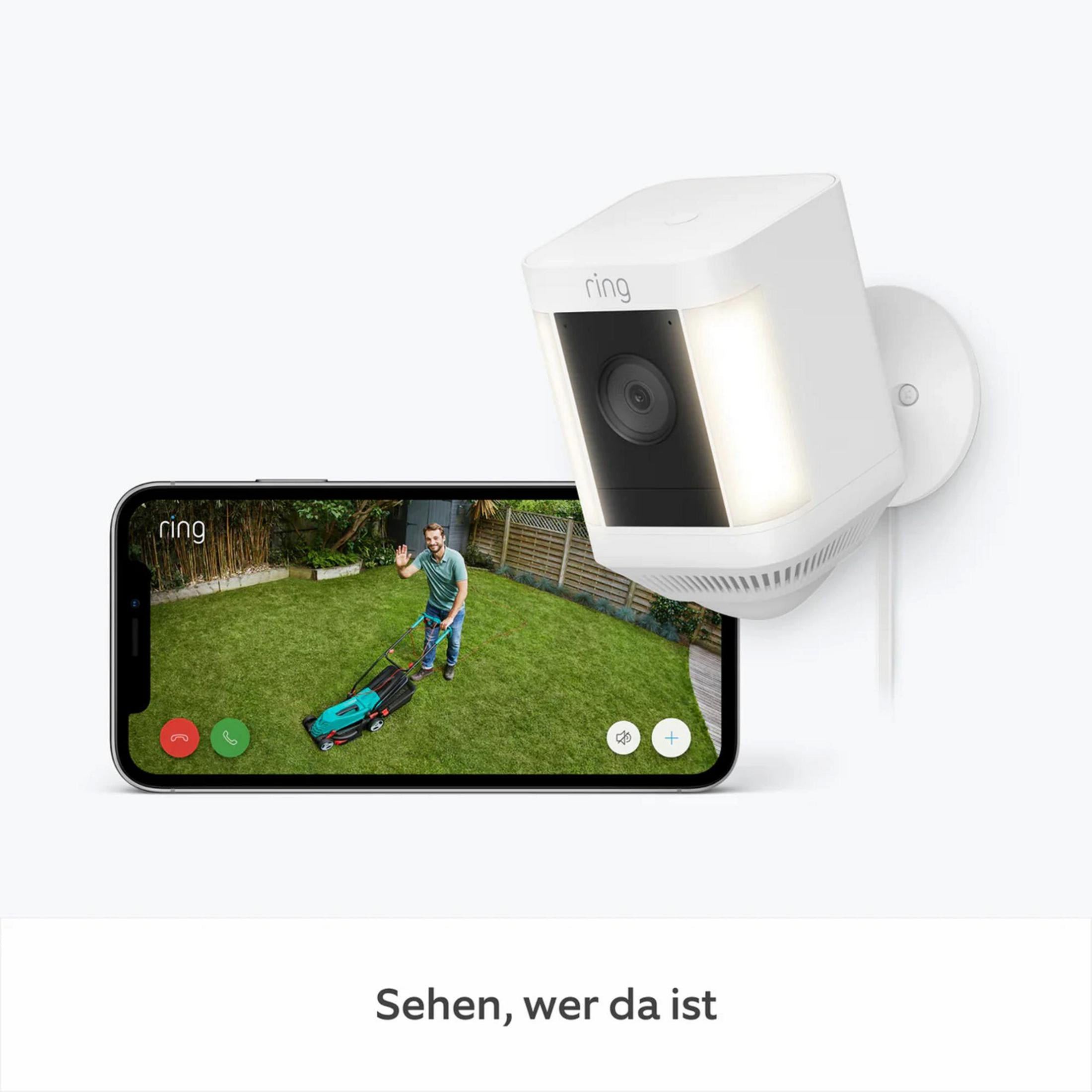 Biała kamera bezpieczeństwa Ring i smartfon z widokiem mężczyzny koszącego trawnik.