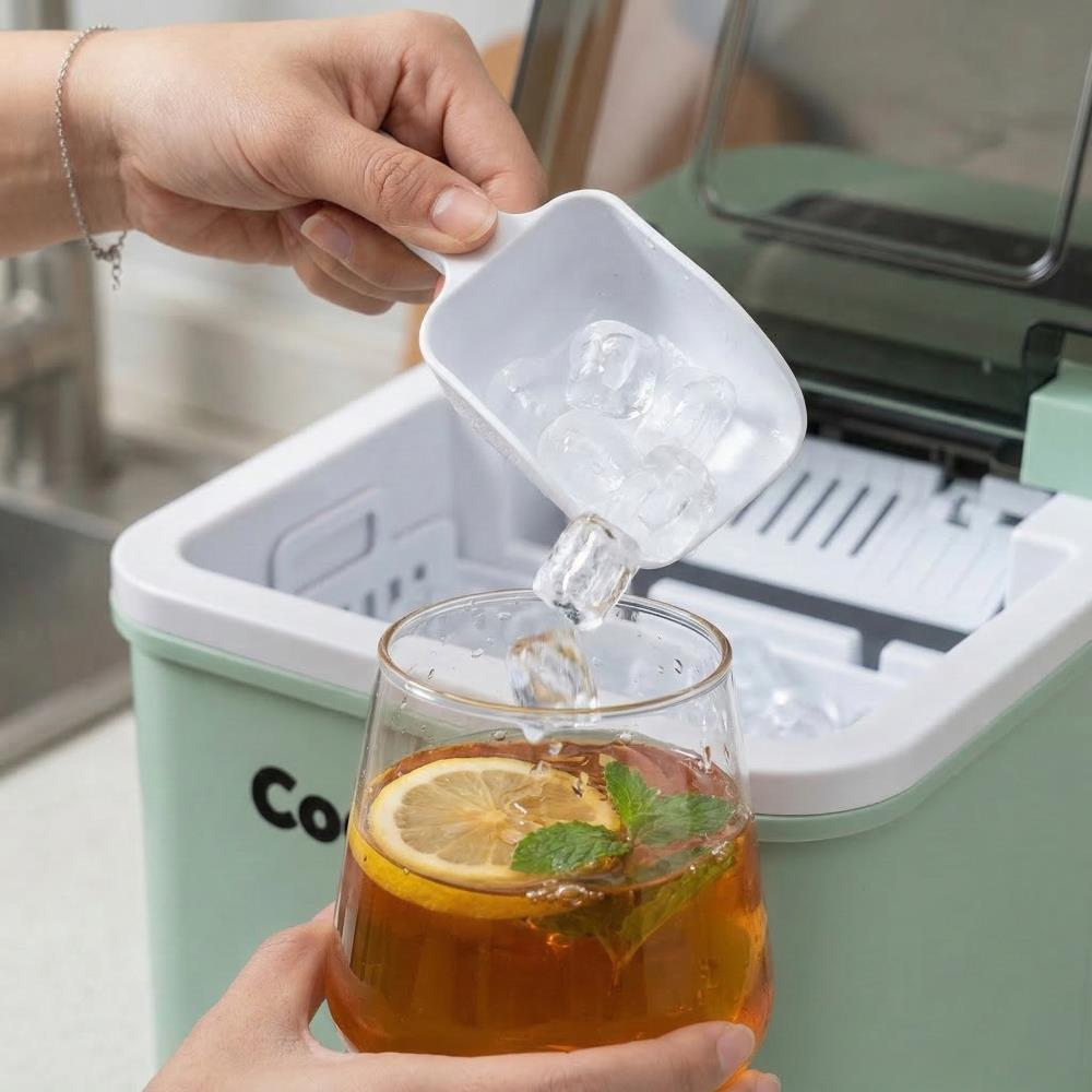 Biri yeşil buz makinesinden limonlu ve naneli soğuk çay bardağına buz küpleri alıyor.
