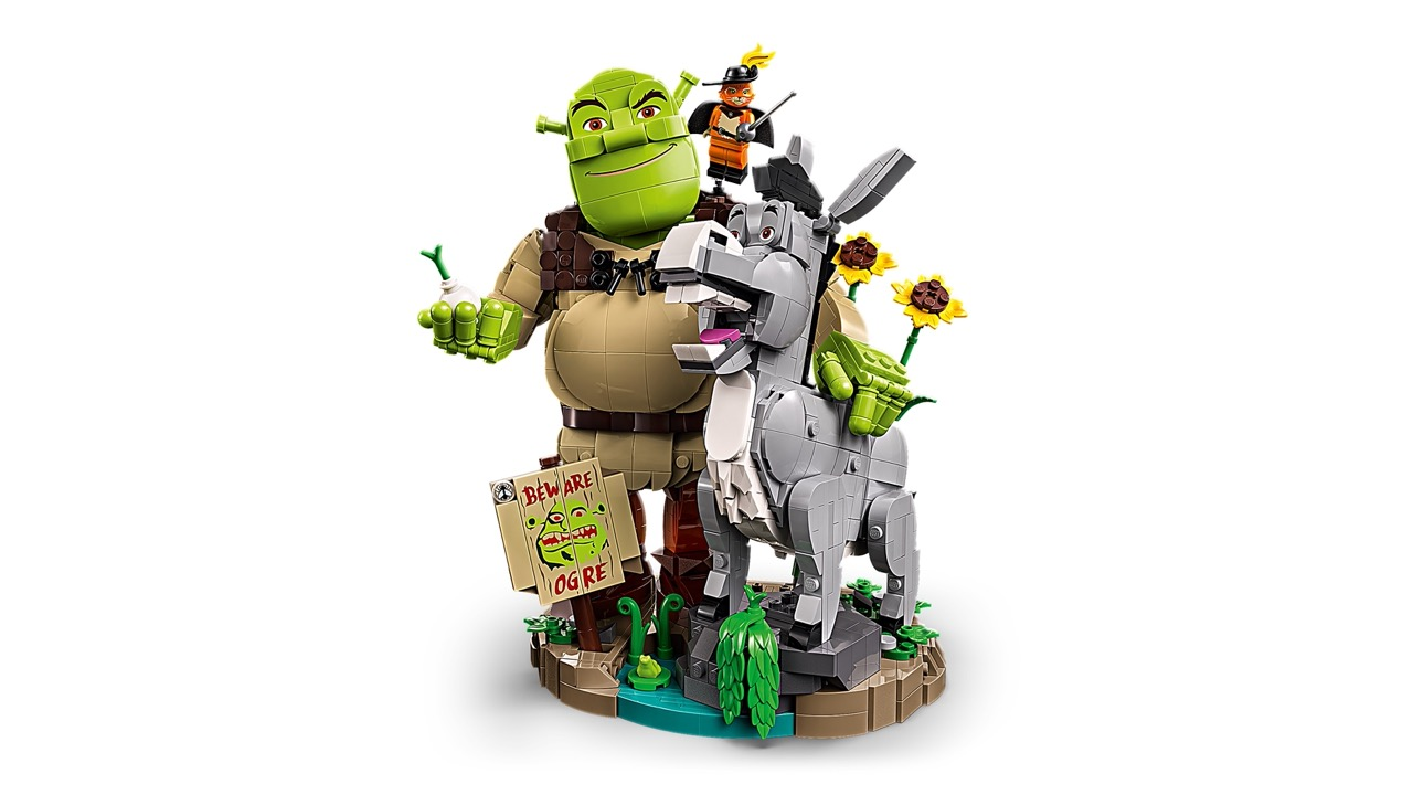 Modelo de Lego de Shrek, Burro y el Gato con Botas con un cartel y flores en una base.