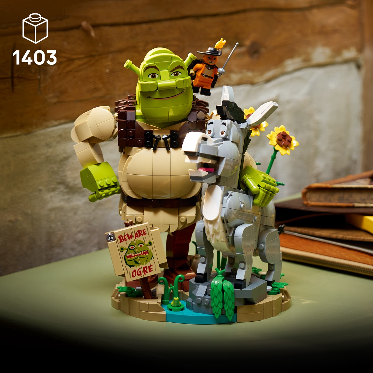 Figuras de Lego de Shrek, Burro y el Gato con Botas junto a un cartel de ogro frente a una pared de madera.