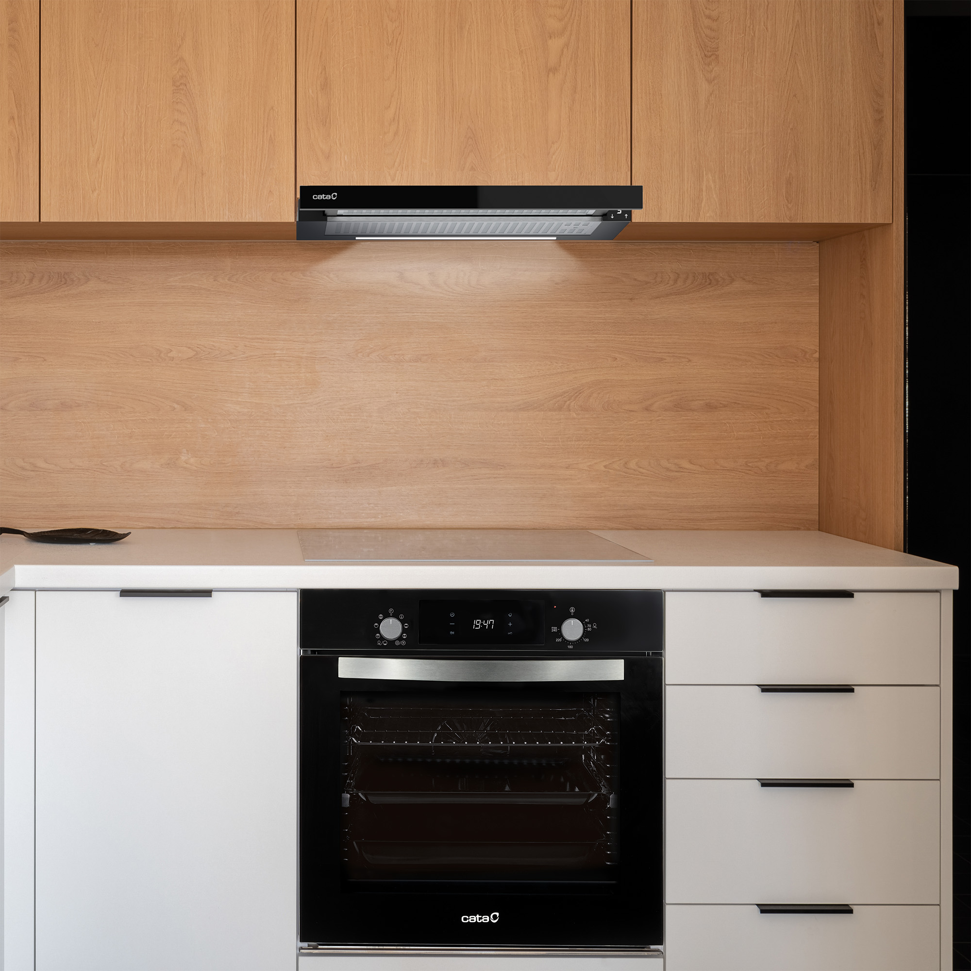 Cocina moderna con armarios de madera, encimera blanca, horno negro y campana extractora.