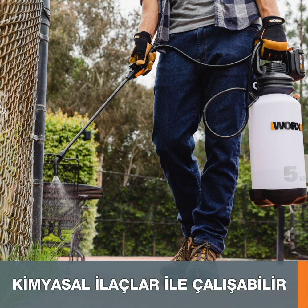 Kot pantolonlu ve eldivenli bir adam Worx sprey şişesi tutuyor ve bahçede bir çiti ıslatıyor.