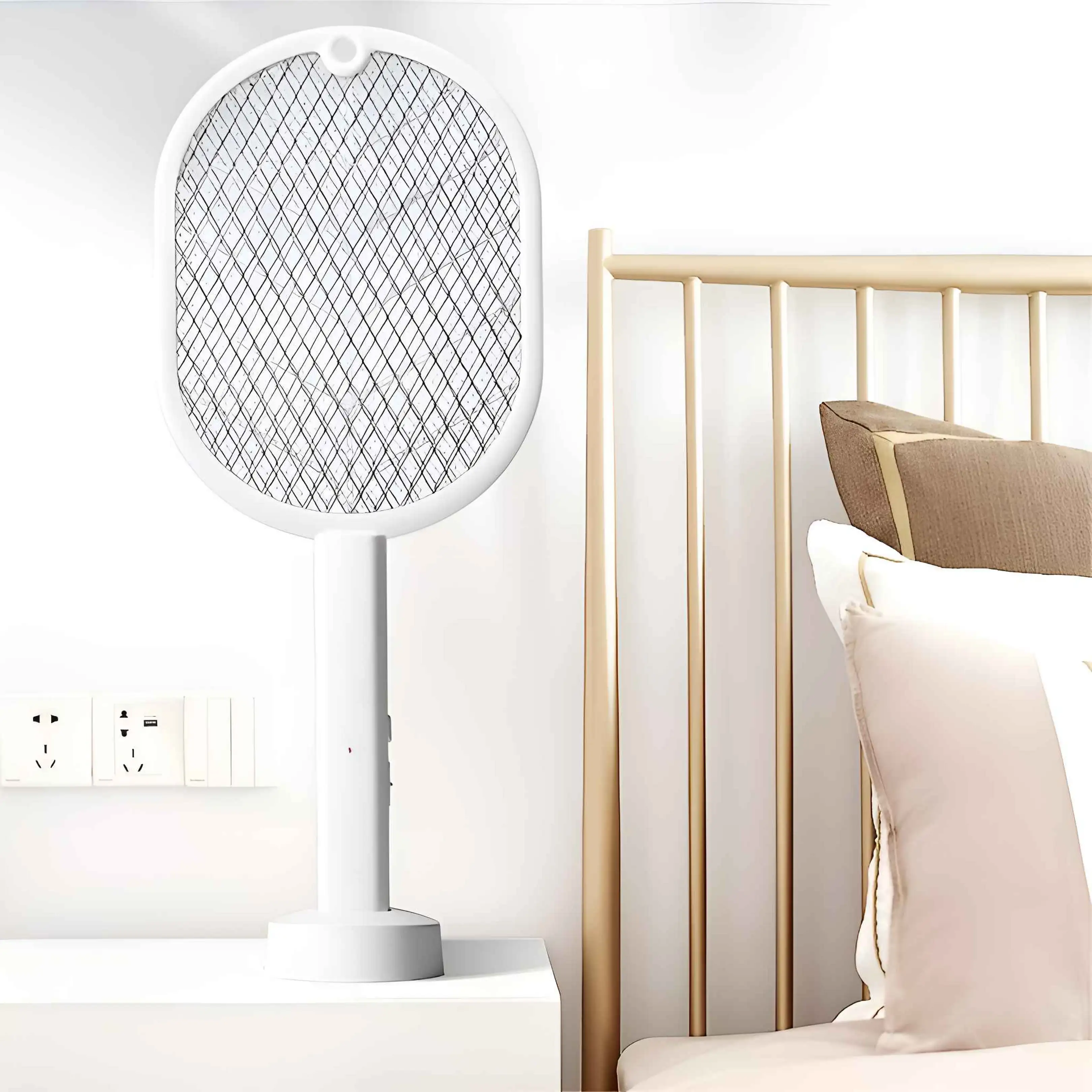 Eine weiße elektrische Fliegenklatsche steht auf einem Nachttisch neben einem Bett mit braunen und weißen Kissen.