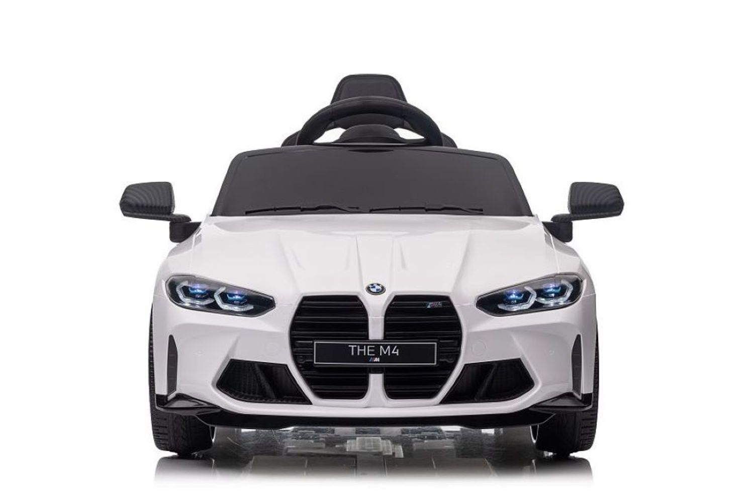 Ein weißes BMW M4 Kinder-Elektroauto von vorne mit eingeschalteten Scheinwerfern.