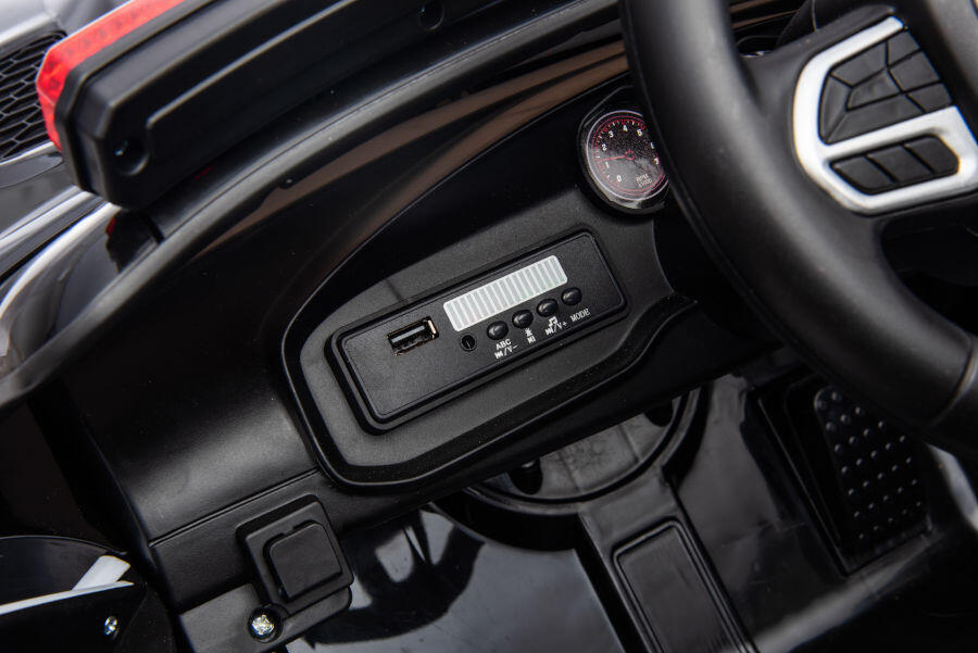 Nahaufnahme des Armaturenbretts eines Spielzeugautos mit USB-Anschluss und Musiksteuerung.