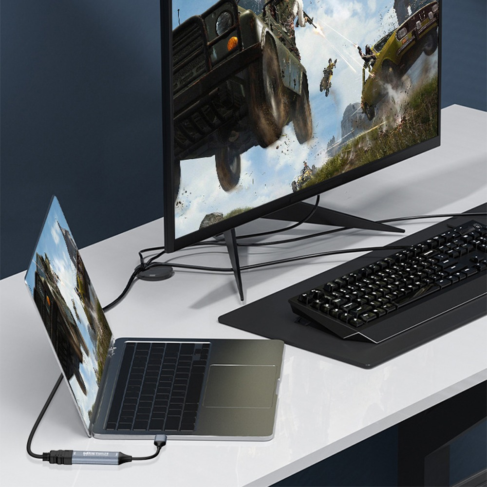 Ein Laptop ist über ein Kabel mit einem großen Computermonitor auf einem weißen Schreibtisch verbunden.