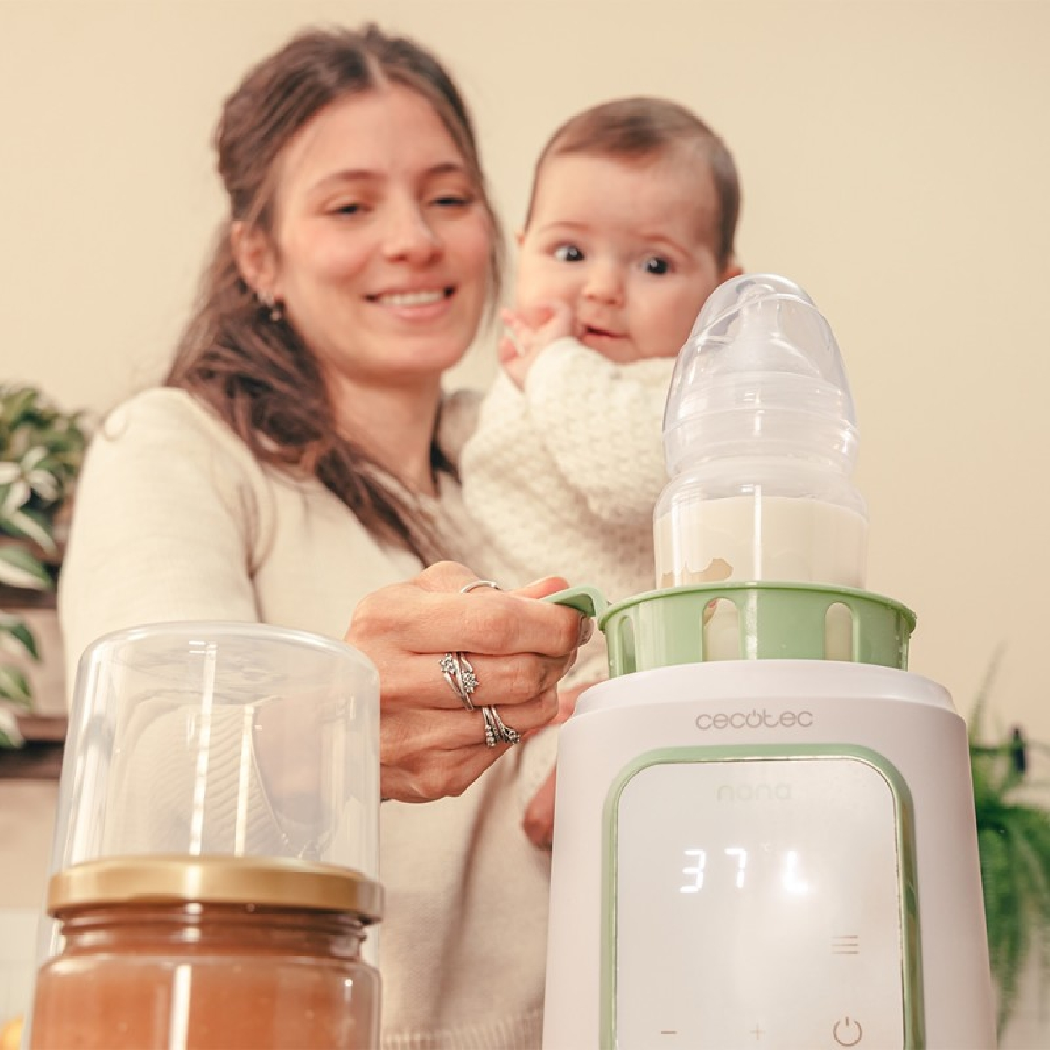 Eine Frau hält ein Baby und eine Flasche in einem Flaschenwärmer mit Anzeige.