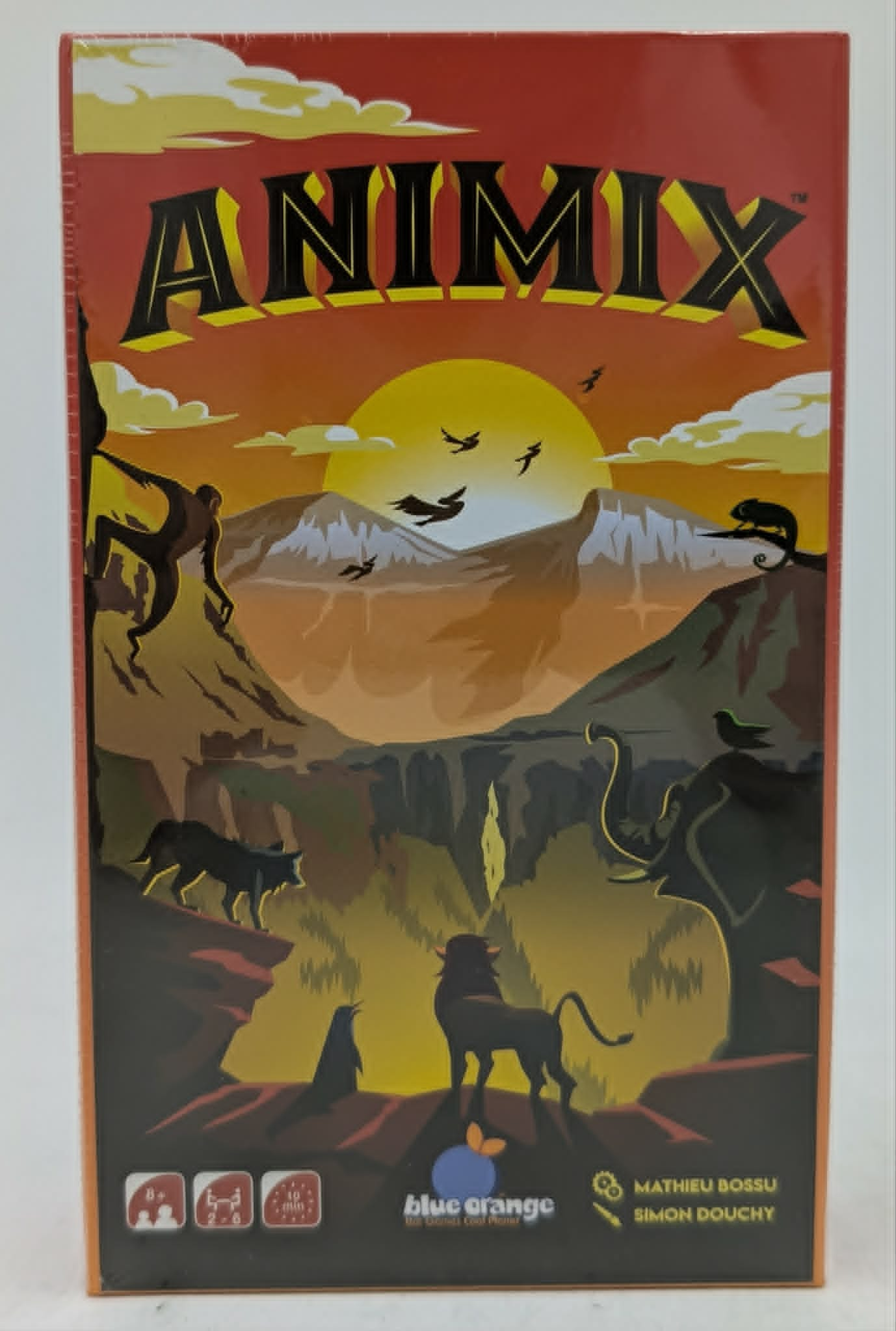 Caja del juego Animix con siluetas de varios animales frente a un paisaje montañoso y puesta de sol.