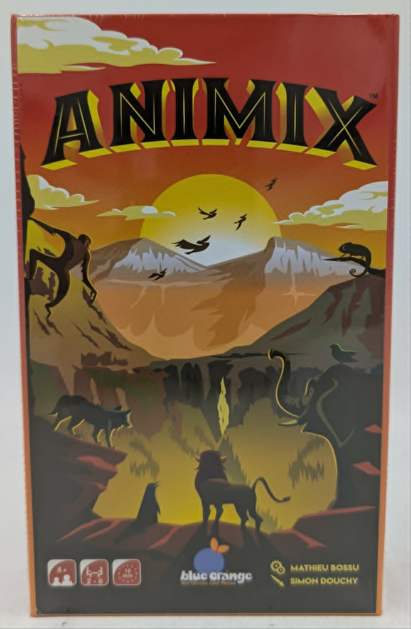 La caja del juego Animix muestra un paisaje al atardecer con animales en silueta como un león, un mono y un elefante.