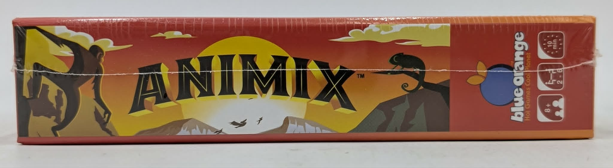 Vista lateral de la caja del juego Animix en naranja, con siluetas de animales, puesta de sol y logotipo.
