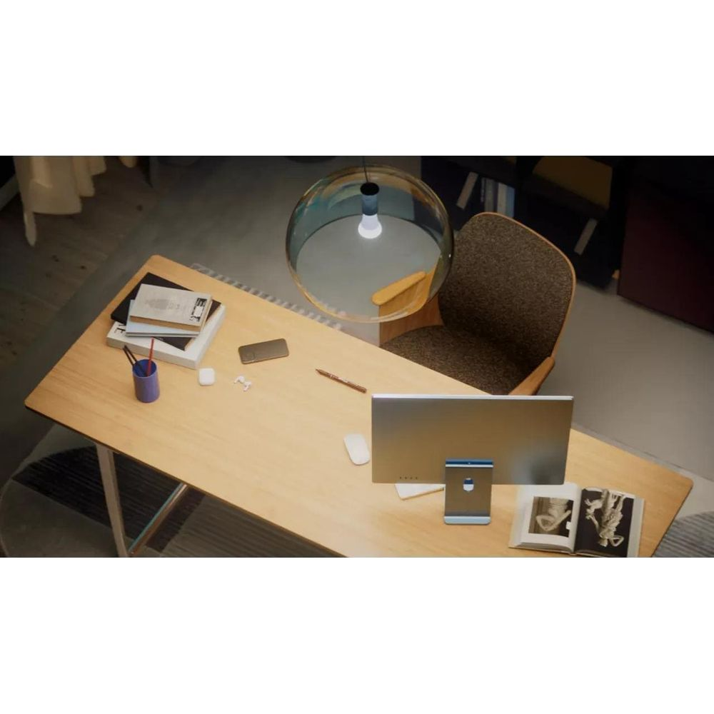 Draufsicht auf einen Holztisch mit einem Computer, einem Buch, Stiften und einer Hängeleuchte von oben.