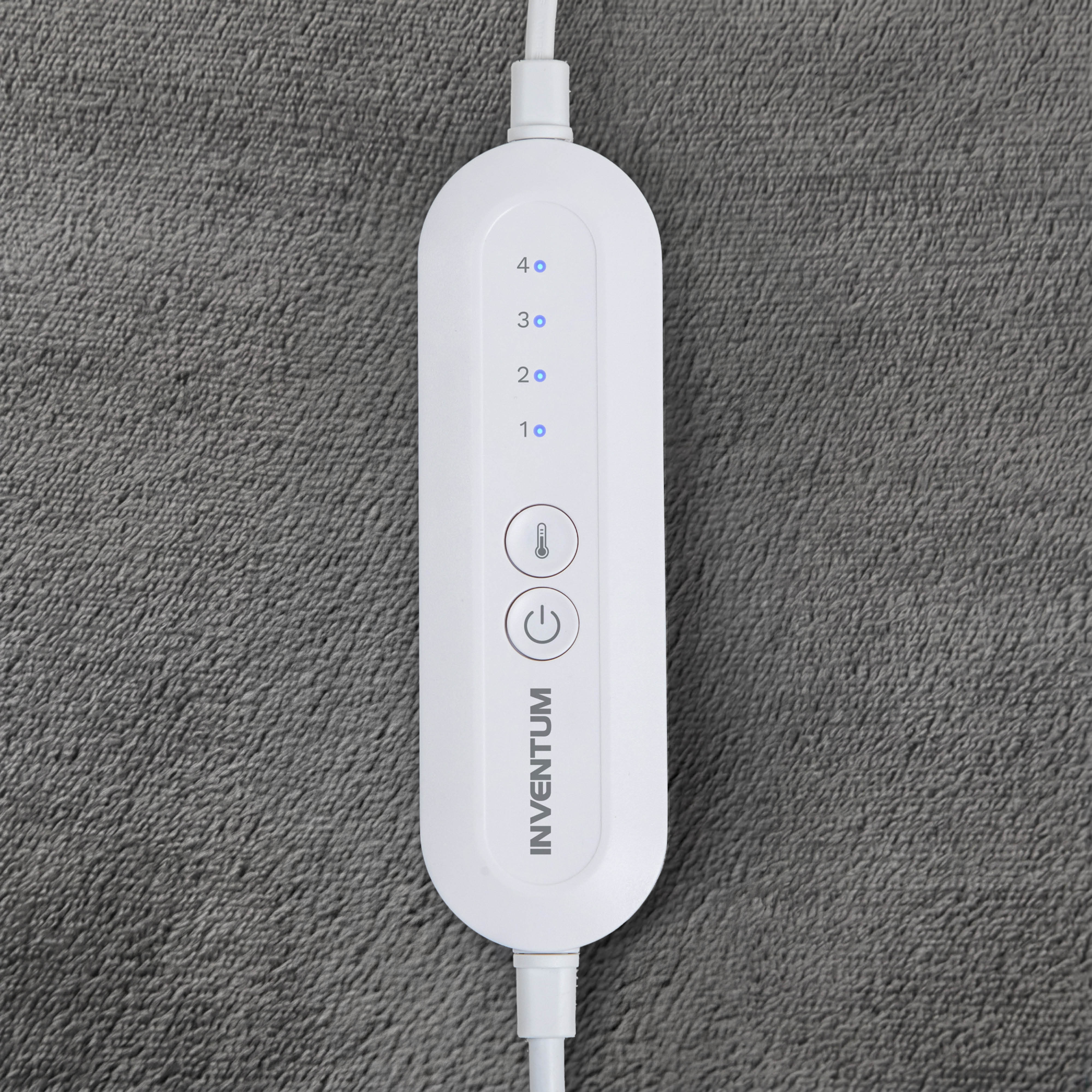 Télécommande blanche de couverture chauffante Inventum avec quatre niveaux sur fond gris.