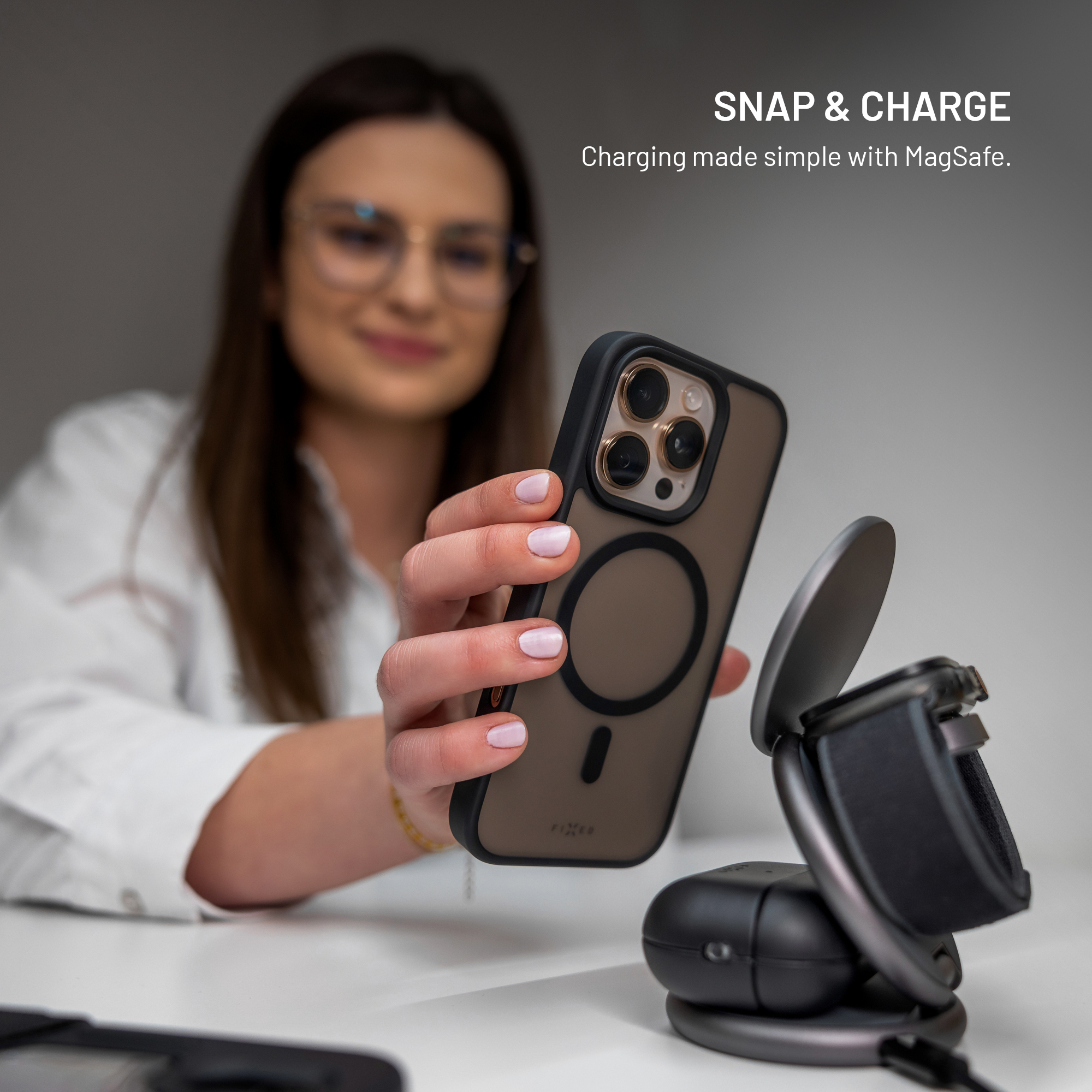Eine Frau hält ein Smartphone neben einer Ladestation mit Text SNAP & CHARGE.