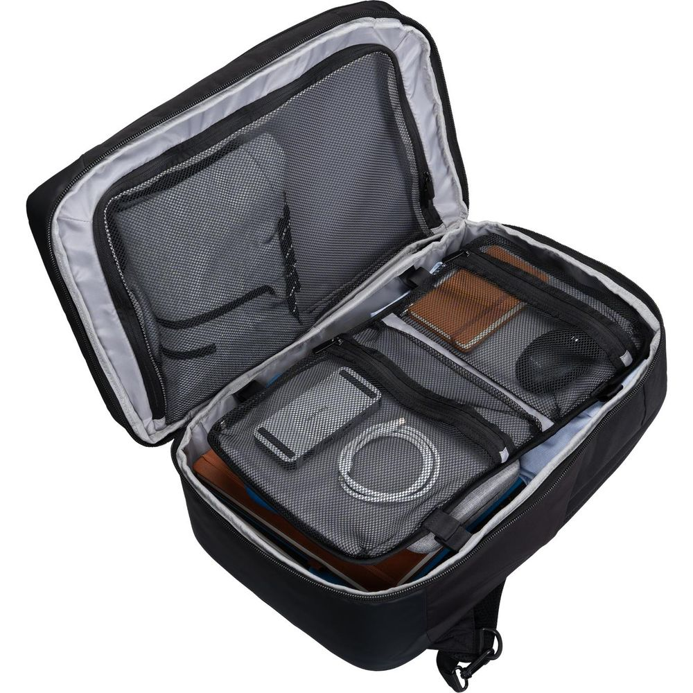 Ein offener schwarzer Rucksack mit mehreren organisierten Fächern, Netztaschen und Zubehörteilen im Inneren.