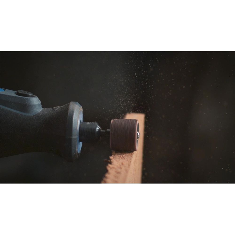 Ein rotierendes Schleifwerkzeug schleift die Kante eines Holzbretts, wobei feiner Staub in der Luft schwebt.