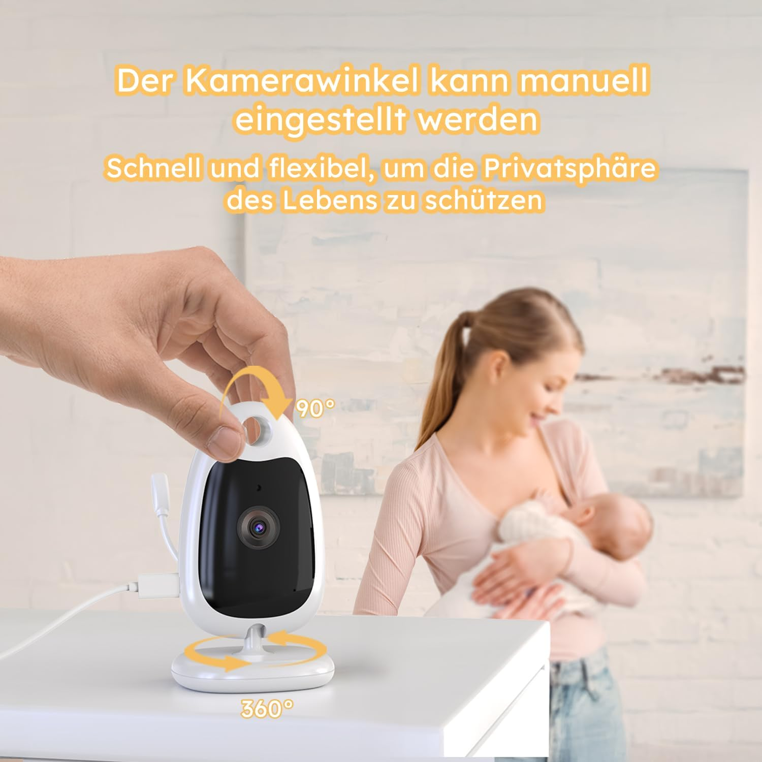 Eine Hand verstellt eine weiße Babykamera auf einem Tisch, während im Hintergrund eine Frau ein Baby hält.
