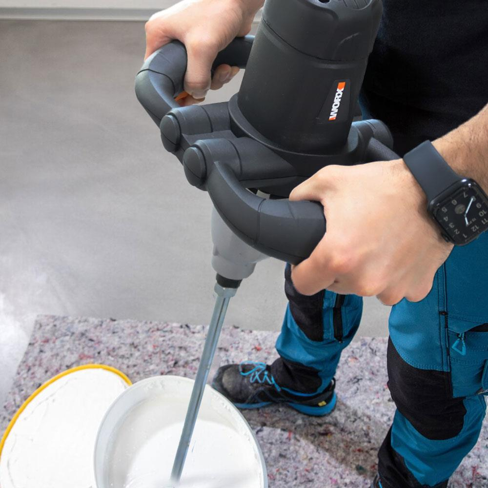 Siyah Worx karıştırıcıyı tutan, kovada beyaz boya karıştırılan kişi.