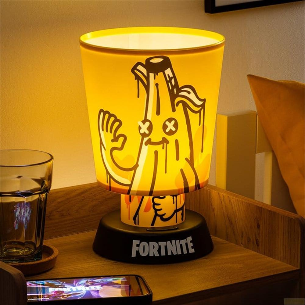 Gelbe Fortnite-Nachtlampe mit Peely-Design auf einem Holznachttisch neben einem Glas Wasser und einem Smartphone.