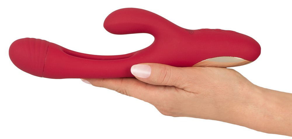 Eine Hand hält einen roten, ergonomisch geformten Vibrator mit goldenen Details vor weißem Hintergrund.