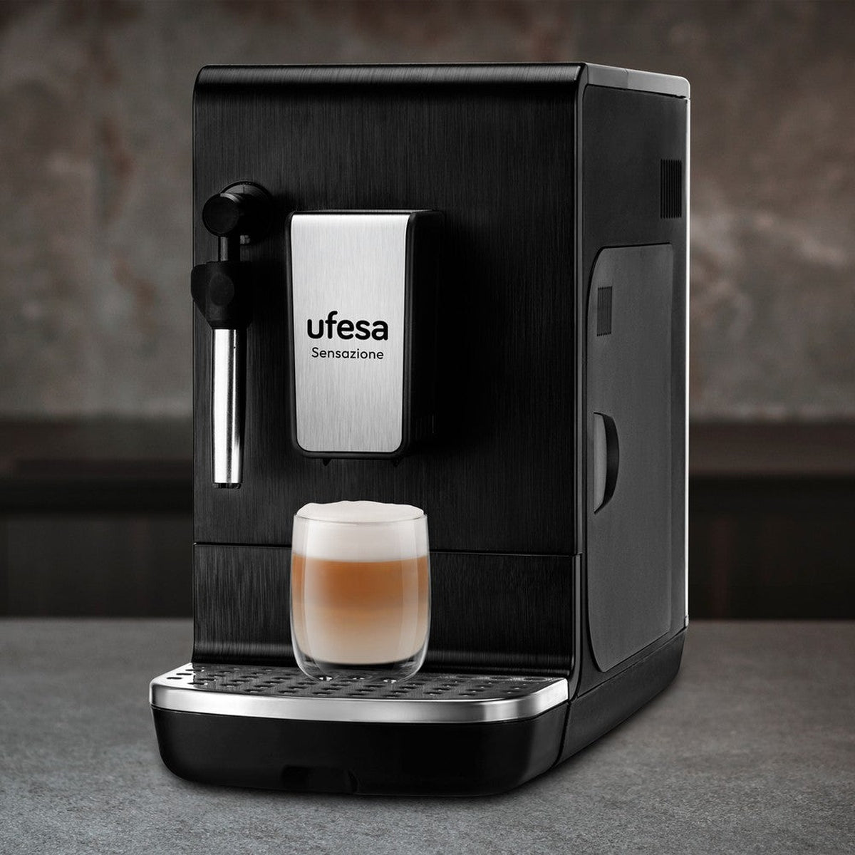 Cafetera negra Ufesa Sensazione con una taza de café sobre superficie gris.