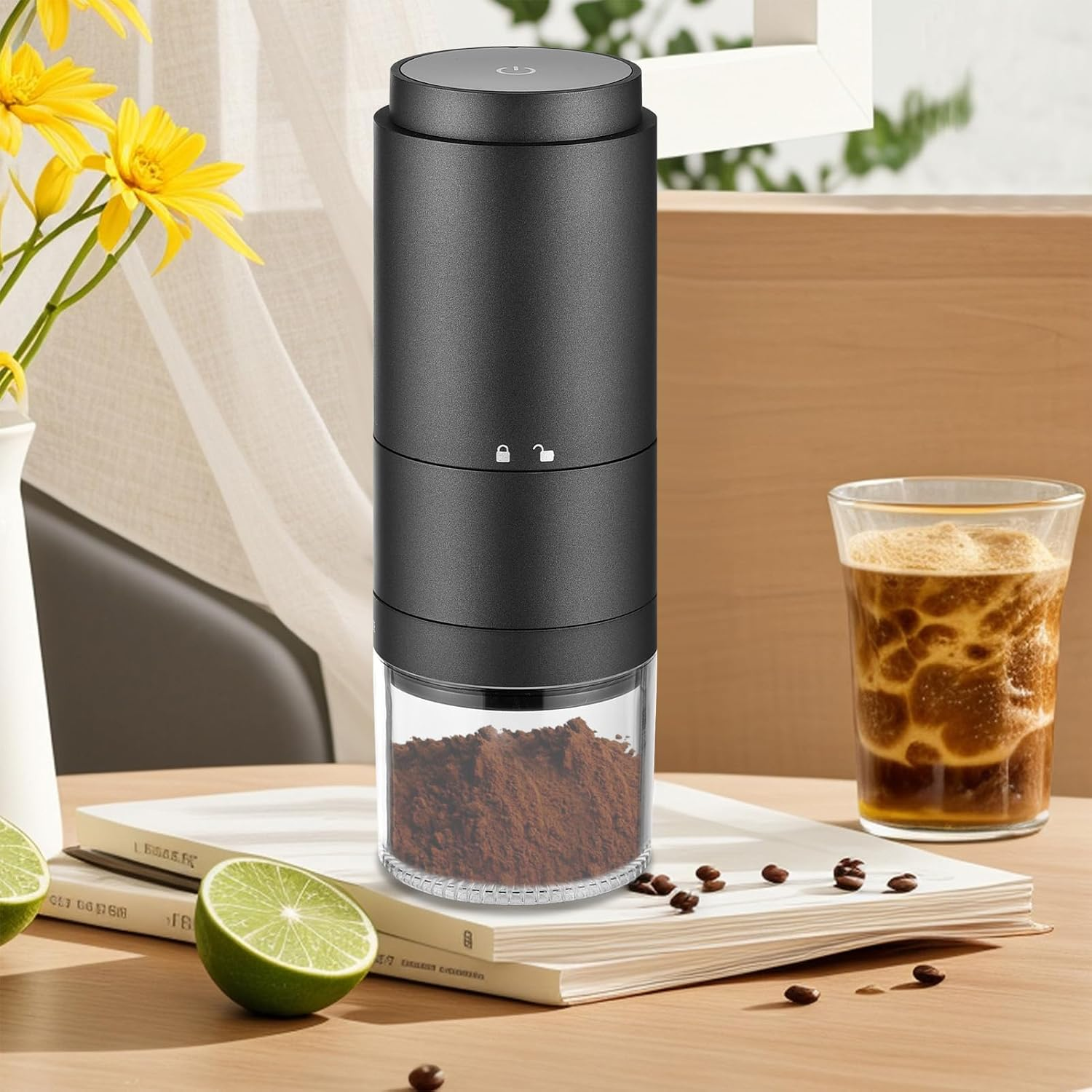 Schwarze Kaffeemühle auf Büchern mit Kaffeepulver, Kaffeebohnen, Limette und Eiskaffee.