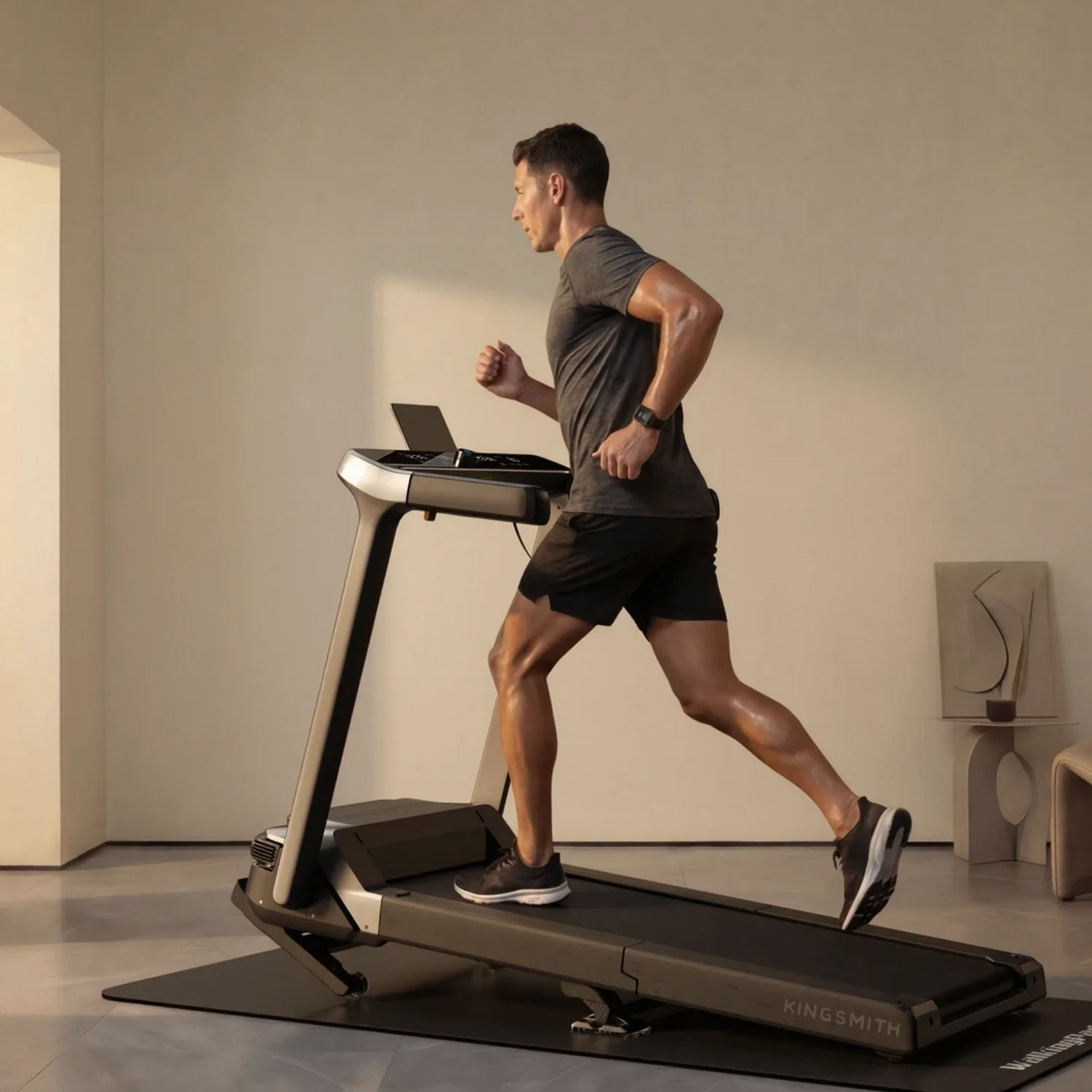 Un hombre atlético corriendo en una caminadora KingSmith en una habitación luminosa y minimalista.