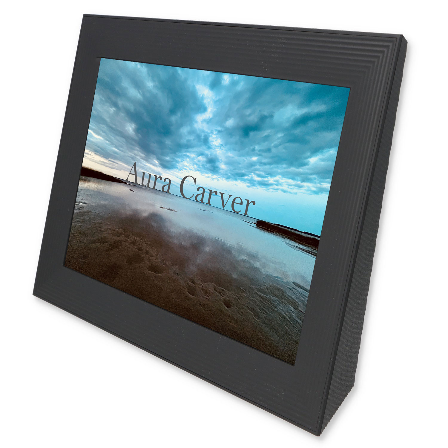 Ein schwarzer digitaler Bilderrahmen mit Text "Aura Carver" zeigt eine Strandlandschaft mit dramatischem Himmel.