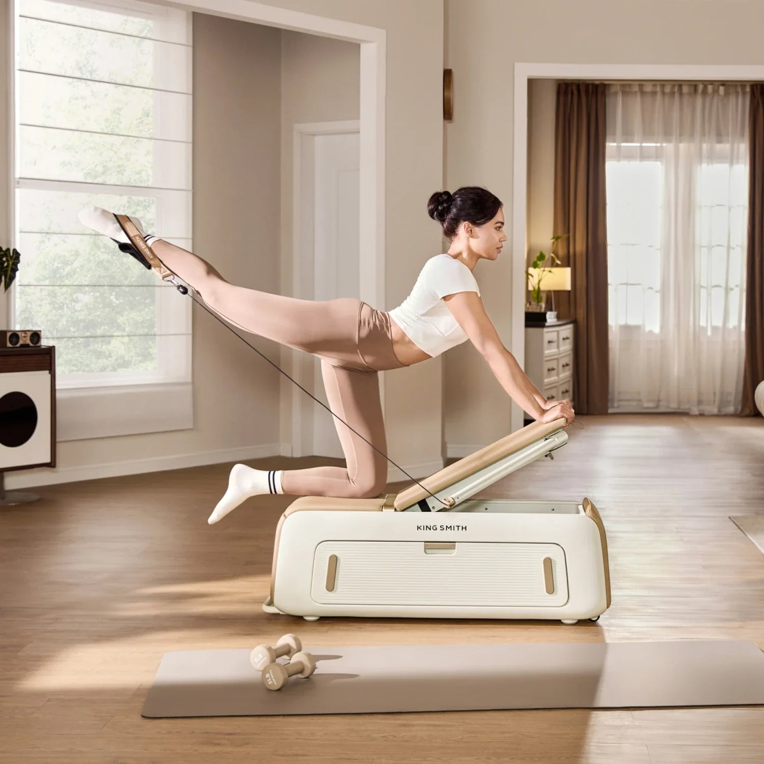 Una donna in abbigliamento sportivo si inginocchia su una macchina per pilates King Smith estendendo una gamba.