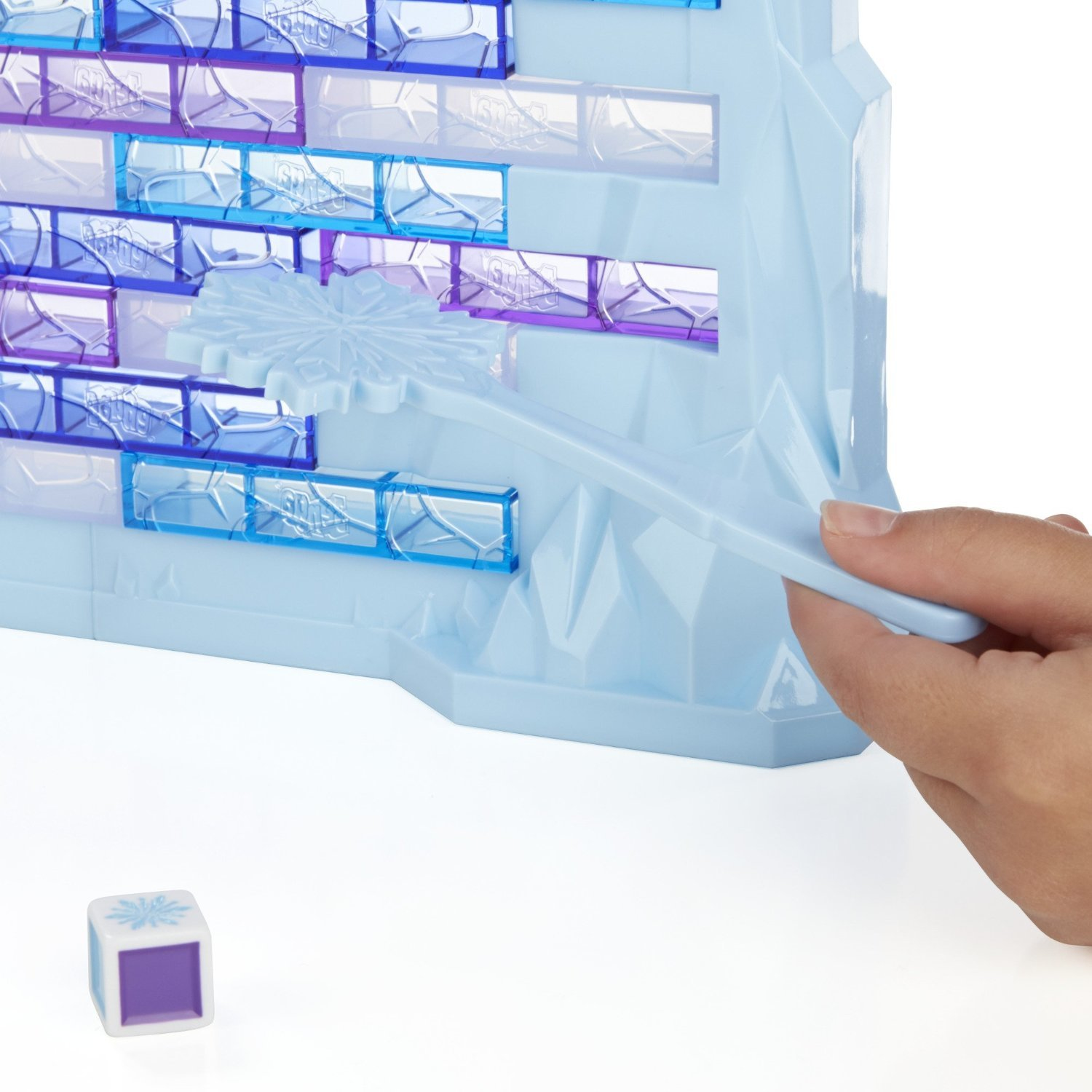 Hand hält Hammer, um blauen Eisblock aus Wand zu schlagen, mit Würfel vorne.