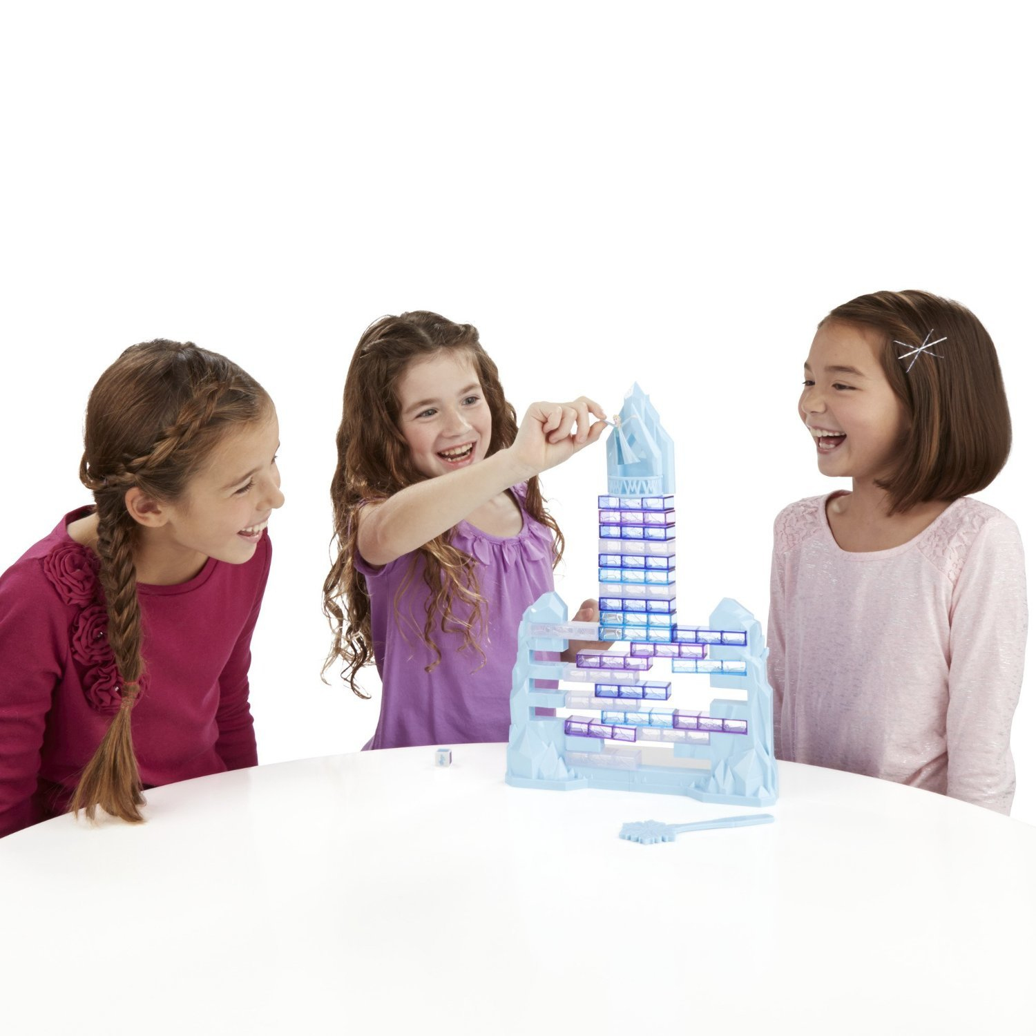 Drei fröhliche Mädchen spielen an einem weißen Tisch ein blaues Turmspiel.